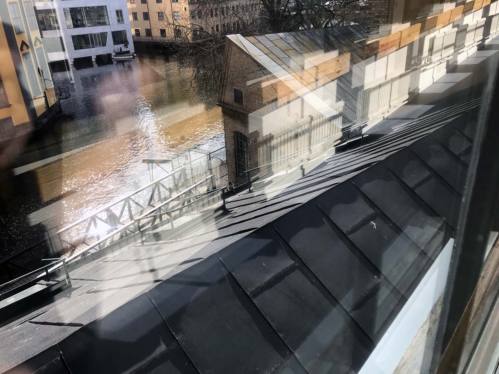 Utsikt över tak vid Motala ström och speglingar i glasruta
